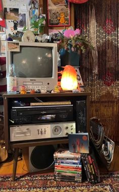 an old fashioned tv sitting on top of a wooden stand next to a pile of books