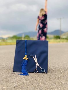 a graduation cap and pair of scissors sitting on the ground in front of a woman