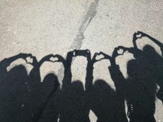 the shadow of several people making a heart with their hands