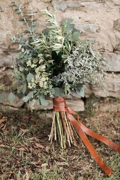 a bunch of flowers that are sitting on the ground in front of a stone wall