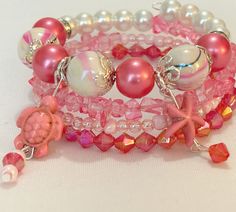 This tropical bracelet features 4 layers of pink beads accented with a turtle charm as well as a starfish charm. It's made with memory wire so there's no need for a clasp and it will fit most wrist sizes! Adjustable Pink Multi-strand Beaded Bracelets, Pink Adjustable Multi-strand Beaded Bracelets, Adjustable Multi-strand Pink Jewelry, Pink Multi-strand Beaded Bracelets Gift, Adjustable Pink Stackable Charm Bracelet, Pink Multi-strand Beaded Bracelets, Adjustable Stackable Pink Charm Bracelet, Pink Multi-strand Bracelets For Gifts, Pink Multi-strand Bracelet As A Gift