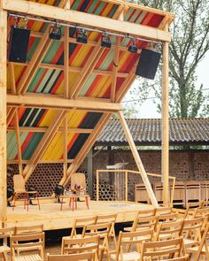 an outdoor stage set up with wooden chairs