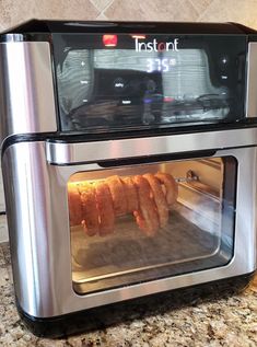 a toaster oven with several pieces of food cooking in it on top of a counter