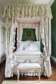 a white bed sitting under a canopy in a bedroom next to a rug and window