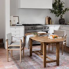 a kitchen with an oven, table and chairs in the middle of it on a rug