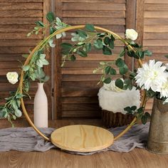 a vase with flowers and greenery is sitting on a table next to a gold plate