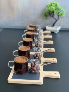 there are many cups and spoons lined up on the table with coffee beans in them