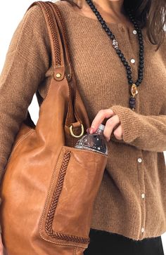 Bolsa Nova Italian Washed Leather Collection. Designed in NY, made in Florence, Italy. Features: Expertly fashioned from supple, vegetable-tanned leather, the Julia Slouchy Tote (Cognac) boasts two side open pockets adorned with elegant braided embellishments for a touch of bohemian flair. The roomy interior provides practical storage options with two open pockets and a zippered pocket to secure your essentials. Full top zip main closure. This versatile tote is the perfect choice for any occasio Elegant Leather Shoulder Bag With Pockets, Elegant Brown Shoulder Bag With Pockets, Slouchy Tote, Outfit Wedding Guest, Oxford Heels, Antique Brass Hardware, Practical Storage, Platform Slippers, Leather Cleaning