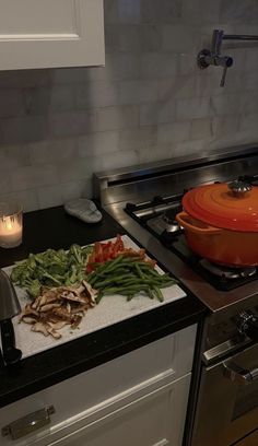 a stove top oven sitting next to a cutting board with vegetables on it