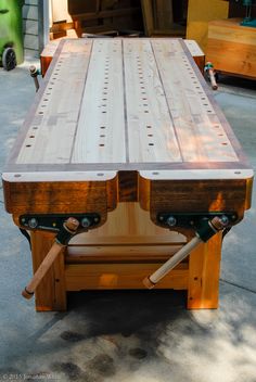 a table made out of wood with two wheels on it