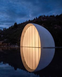 a large white circular structure sitting on top of a body of water under a cloudy sky