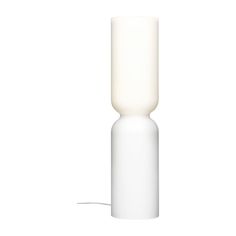 a white table lamp sitting on top of a white floor next to a light bulb