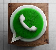 a green phone sitting on top of a wooden table next to a white tiled wall