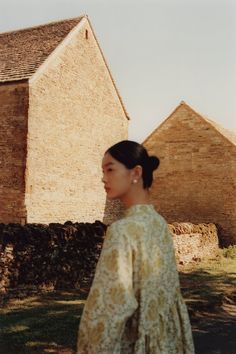 a woman standing in front of a brick building and looking off into the distance with her hand on her hip