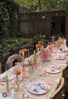 a long table with plates and candles on it in the middle of an outdoor area