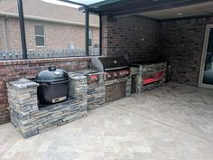 an outdoor bbq area with grills and chairs on the outside patio, surrounded by brick walls