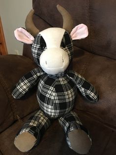 a stuffed cow sitting on top of a brown couch