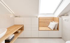 a bathroom with white walls and wooden shelves on the wall, along with a skylight