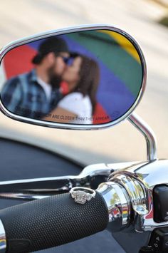 a couple kissing in the mirror of a motorcycle