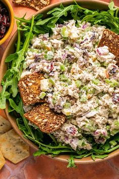 a bowl filled with salad next to crackers