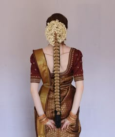 a woman with her hair in the shape of a flower is wearing a brown sari