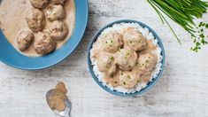 meatballs and gravy in a blue bowl on top of rice with green onions