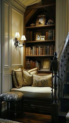 a living room filled with lots of books on top of a book shelf next to a stair case