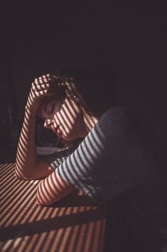 a woman is sitting on a bench with her hands behind her head and looking down