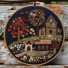 an embroidery kit with a house and trees on the front, surrounded by colorful flowers