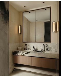 a bathroom with two sinks, mirrors and lights on the wall in it's corner