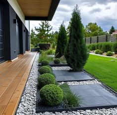 an outdoor area with wooden decking and graveled walkway leading to the front door