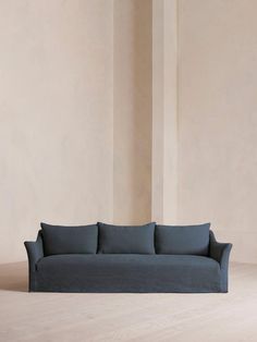 a blue couch sitting on top of a hard wood floor next to a white wall