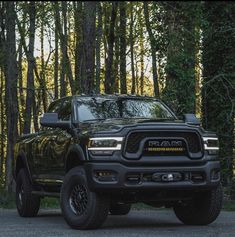 a black ram truck parked in front of some trees