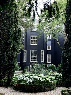 a black house surrounded by trees and plants