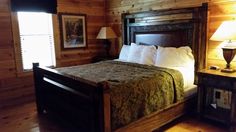 a bed in a room with wooden walls and wood flooring next to a night stand