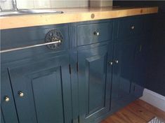 a kitchen with blue cabinets and wooden counter tops, including a sink that has brass knobs on it