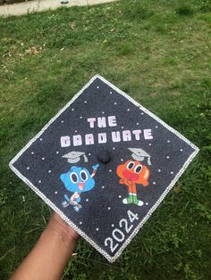 a graduation cap that says the graduate and two cartoon characters are on top of it