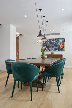 a dining room table with blue chairs and a painting on the wall in the background