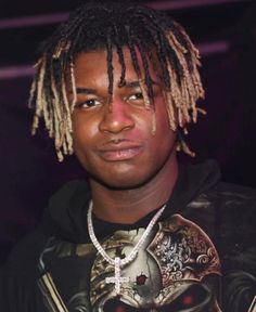 a young man with dreadlocks and a skull t - shirt is looking at the camera