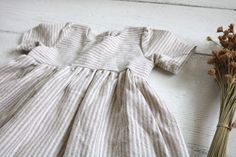 2-3 WEEK TURNAROUND TIME. This tan and cream striped cotton/linen handmade dress is the perfect addition to any little's wardrobe! Though great for all year cuteness! Perfect fall and winter with elbow length sleeves. Or summertime fun with the tank version. Dress is a elbow-sleeved or sleeveless, with a lined, slightly curved front bodice. Three wooden button closures in the back of the dress of the 3/4 sleeved version. Tank version has a V-back and 1 button. This fabric is a linen cotton blend Cute Short Sleeve Dress With Button Closure, Cute Cotton Button-up Dress, Cute Button-up Cotton Dresses, Cream Cotton Dress With Buttons, Cute Button-up Dress With Buttons, Beige Cotton Dress With Buttons, Cute Fitted Button-up Dress, Cute Daywear Dresses With Buttons, Cute White Dresses With Buttons