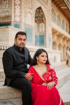 a man and woman sitting on steps in front of a building