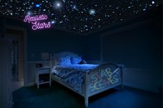 a bed room with a neatly made bed and stars on the ceiling above it at night