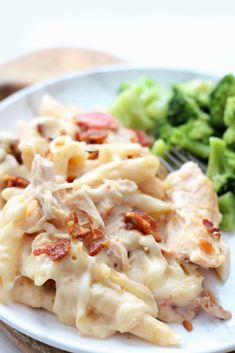 a white plate topped with pasta and broccoli on top of a wooden table