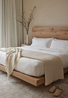 a bed with white sheets and pillows next to a window