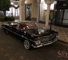 an old black car parked in front of a building