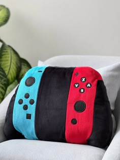 two nintendo wii controllers pillows sitting on top of a couch next to a potted plant