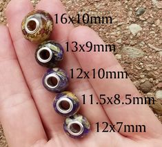 three beads in the palm of someone's hand with measurements for each bead