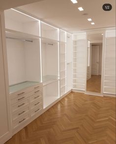 an empty room with white shelves and drawers