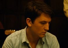 a young man sitting in front of a guitar