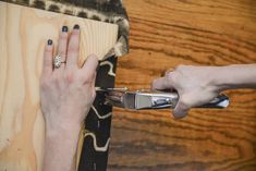 a person using a pair of scissors to cut something on a piece of plywood